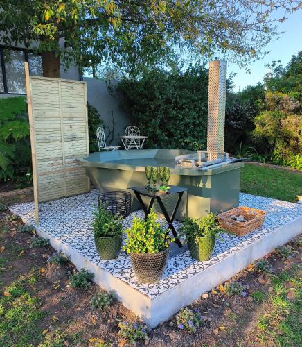 a outdoor bathtub with potted plants on a pebble slab at Gilgal Guest Accommodation in Onder-Papegaaiberg