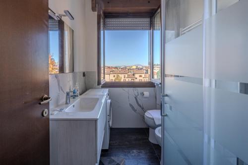 Un baño con lavabo, inodoro y ventana. en Bontempi House, en Pioltello
