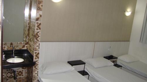 a room with two beds and a sink and a mirror at Calandre Hotel in Sao Paulo