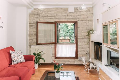 salon z czerwoną kanapą i kominkiem w obiekcie Palladio Apartment - In Centro con Garage, Vista Fiume, Jacuzzi w mieście Vicenza