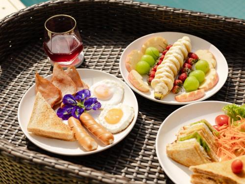 een tafel met drie borden eten en een glas wijn bij L1 Lanta Resort in Koh Lanta