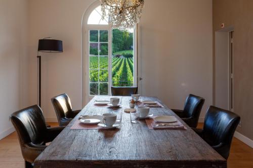 Una gran mesa de madera con sillas y una gran ventana. en le clos des belvals, en Vertus