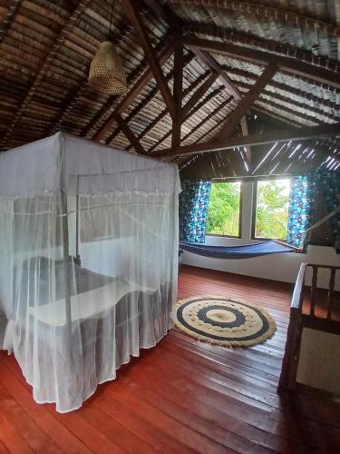 a room with a white curtain and a wooden floor at Villa des îles Nosy Komba in Nosy Komba