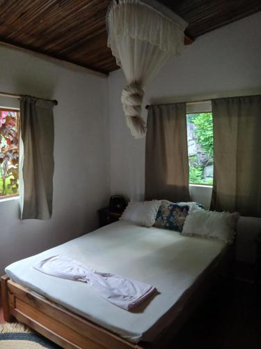 a bed in a bedroom with two windows at Villa des îles Nosy Komba in Nosy Komba