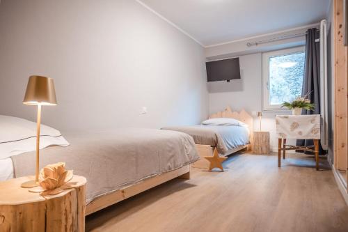 a bedroom with two beds and a table and a window at Garni Pola in Campocologno