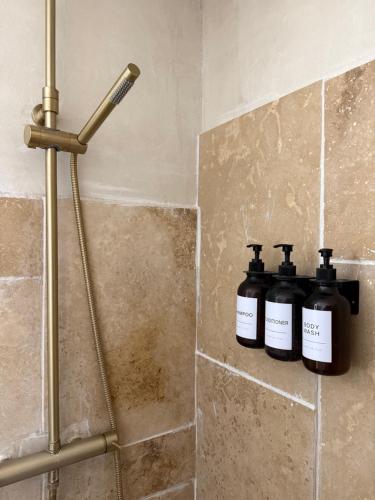 deux bouteilles de savon posées sur une étagère dans une douche dans l'établissement Cocon avec jacuzzi, à Périgny