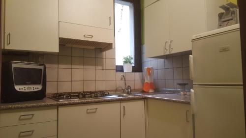 ミラノにあるBnButler - Sempione Apartment - Arco della Paceの白いキャビネット、シンク、電子レンジ付きのキッチンが備わります。