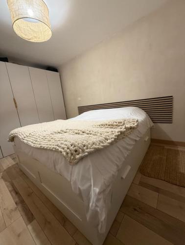 un lit blanc dans une chambre avec un lustre dans l'établissement Cocon avec jacuzzi, à Périgny