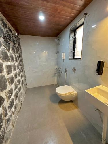 a bathroom with a toilet and a stone wall at Nirvana Bhimashankar Jungle Resort in Bhimashankar
