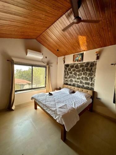 a bedroom with a bed and a large window at Nirvana Bhimashankar Jungle Resort in Bhimashankar