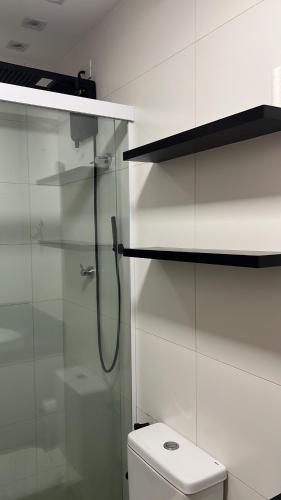 a bathroom with a toilet and a glass shower at Studio Design 3 Lions in Maceió