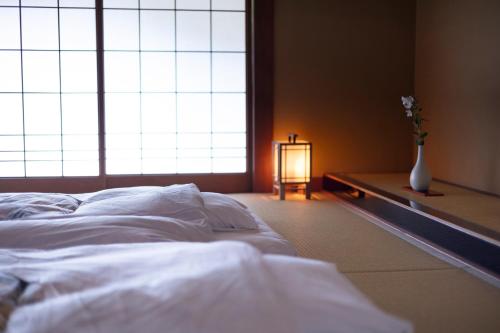 a bedroom with a white bed and a vase with flowers at Tokiwa Bekkan in Toyooka
