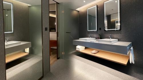 un baño con dos lavabos y dos espejos en W9-Hotel ShangHai PuDong Airport, en Shanghái