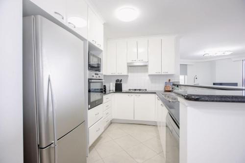 a white kitchen with white cabinets and a refrigerator at Pyrmont 2 Bed Apartment - Prime Location w parking in Sydney