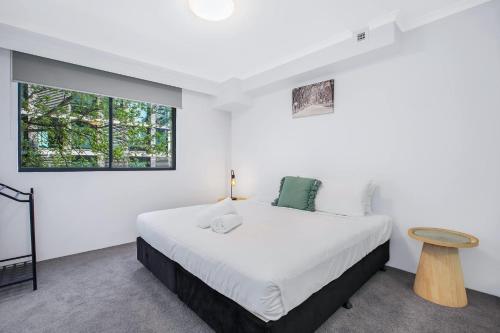 a white bedroom with a bed and a table at Pyrmont 2 Bed Apartment - Prime Location w parking in Sydney