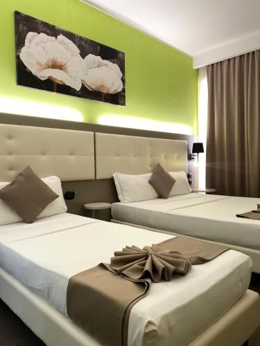 two beds in a hotel room with flowers on the wall at Hotel Stradivari in Milan