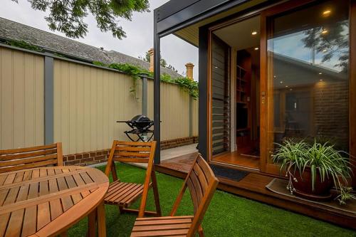 a patio with two wooden chairs and a table at Charming 3-Bedroom Terrace in the Heart of Glebe in Sydney