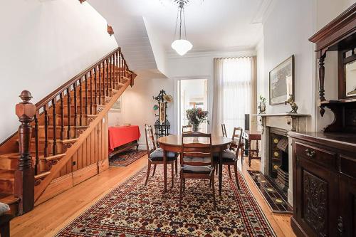 a dining room with a table and a staircase at Charming 3-Bedroom Terrace in the Heart of Glebe in Sydney