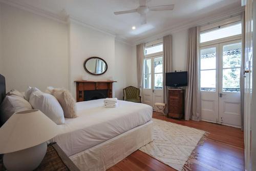 a living room with a white bed and a television at Charming 3-Bedroom Terrace in the Heart of Glebe in Sydney
