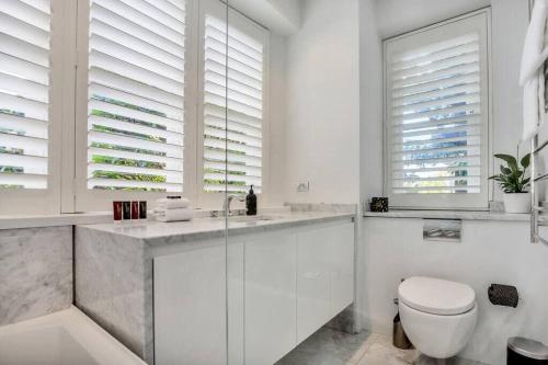 a bathroom with a toilet and a sink and windows at Henrietta's Gem - Close to cafes, shops and more in Sydney