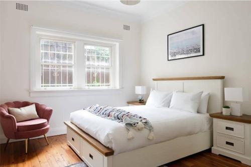 a bedroom with a large white bed and a chair at Edward Escape - Short Walk to Beach in Sydney