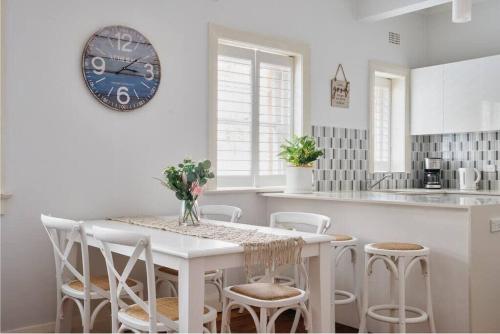 a kitchen with a white table and chairs and a clock at Edward Escape - Short Walk to Beach in Sydney