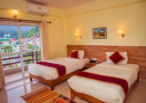 a hotel room with two beds and a window at Hotel Dream Light in Pokhara
