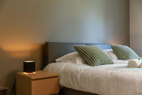 HarelbekeにあるHuswell - Authentic Serene Vacation Hideaway with Pondの緑と白の枕とナイトスタンドが備わったベッド