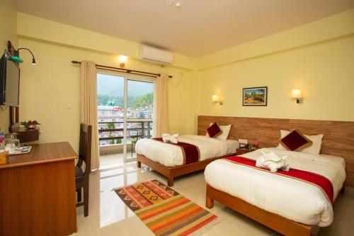a hotel room with two beds and a balcony at Hotel Dream Light in Pokhara
