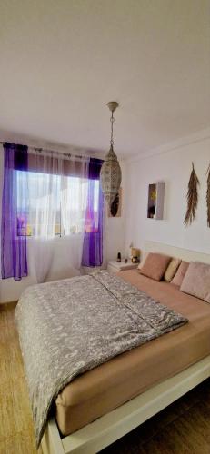 a bedroom with a large bed with purple curtains at Marveo in La Oliva