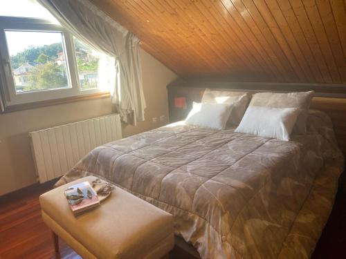 a bedroom with a bed and a table and a window at Casa Vacacional O PIÑEIRO in Piñeiro