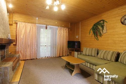 een woonkamer met een bank, een tafel en een televisie bij Котеджі Сім Вітрів in Volosyanka