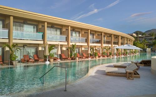 a hotel swimming pool with chairs and an umbrella at Iberostar Selection Fuerteventura Palace in Morro del Jable