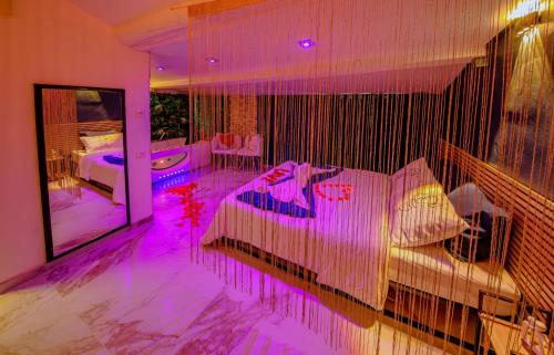 een slaapkamer met een bed met paarse verlichting erop bij Love Room romantique avec jacuzzi - Arles centre in Arles