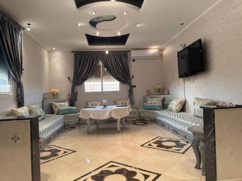 un salon avec des canapés, une table et une télévision dans l'établissement Villa agadir, à Glalcha