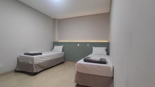 two beds in a room with white walls at Hotel Salvalagio Urupês in Urupês