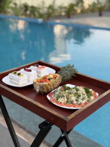 twee borden eten op een tafel naast een zwembad bij Camel Valley Resort & Spa, Igatpuri in Igatpuri