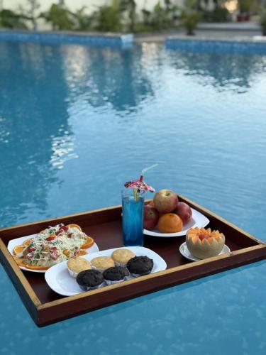 een dienblad met eten op een tafel naast een zwembad bij Camel Valley Resort & Spa, Igatpuri in Igatpuri
