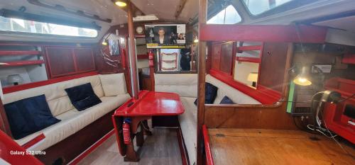 Una pequeña habitación con un sofá y una mesa roja. en Grand voilier avec tout confort, en Cherbourg-en-Cotentin