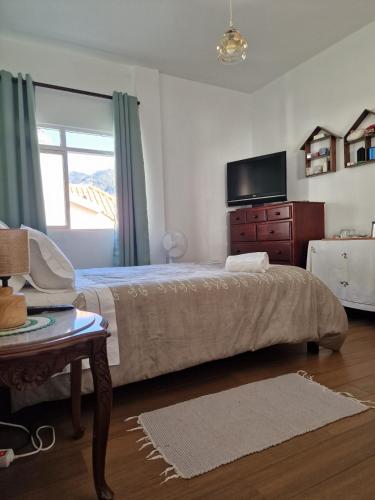 ein Schlafzimmer mit einem Bett, einer Kommode und einem Fernseher in der Unterkunft Nature Brava Stay in Ribeira Brava