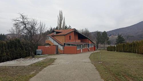 een groot rood huis met een oprit in een veld bij Panorama Borsko jezero in Beljevina