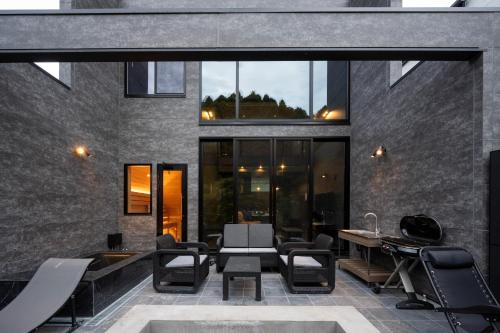 an outdoor patio with chairs and tables and windows at 一棟貸切サウナ付き宿 我忘歳月 清風明月