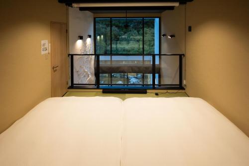 a bed in a room with a window at 一棟貸切サウナ付き宿 我忘歳月 清風明月