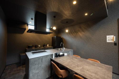 a kitchen with a counter and a table with chairs at 一棟貸切サウナ付き宿 我忘歳月 清風明月