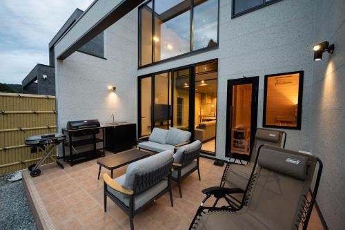a patio with chairs and a table and a desk at 一棟貸切サウナ付き宿 我忘歳月 清風明月