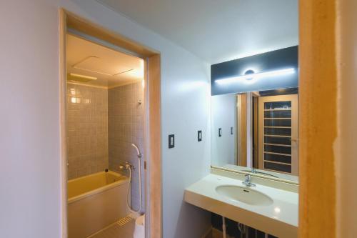 ein Badezimmer mit Waschbecken, Badewanne und Spiegel in der Unterkunft Palcall Tsumagoi Resort Ski & Hotel in Tsumagoi