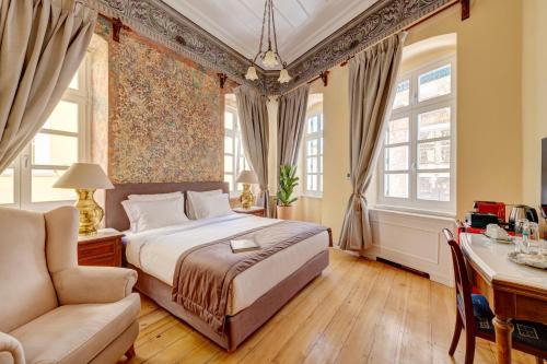 ein Schlafzimmer mit einem Bett und einem Stuhl und Fenstern in der Unterkunft Palazzo Santa Maria - Historic Hotels of Europe in Ermoupoli