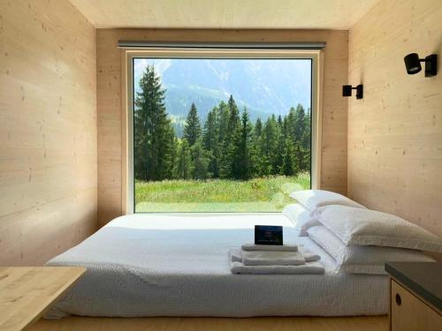 EccheにあるVivere l'inverno tra i prati di Sappadaの大きな窓のある部屋のベッド