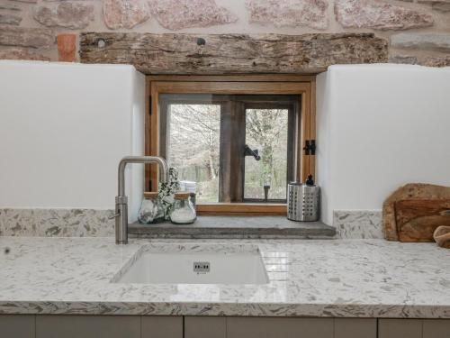 a kitchen counter with a sink and a window at Walnut Cottage in Usk