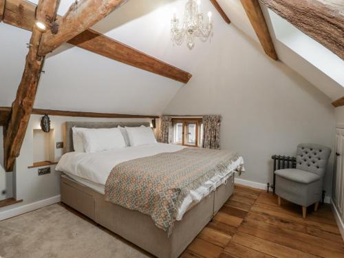 a bedroom with a large bed and a chair at Walnut Cottage in Usk